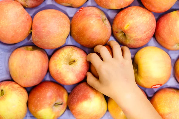 Childs mano tomando manzana roja de la exhibición llena de frutas — Foto de Stock