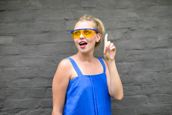 Beautiful young joyful lady gesturing eureka on grey wall background — Stock Photo, Image