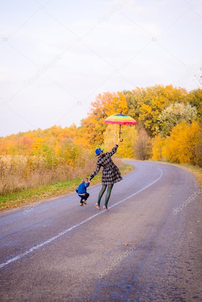 Happy mother and son having fun on autumn countryside road