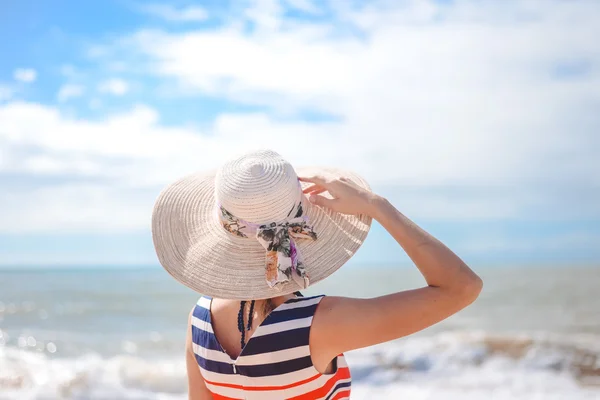 Backview of elegant lady in straw hat standing on seaside — Stock Photo, Image