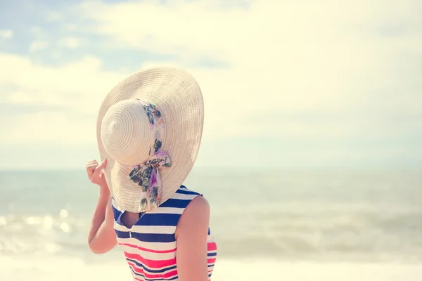 Mooie jonge dame in stro hoed rustend op zonnige kust — Stockfoto