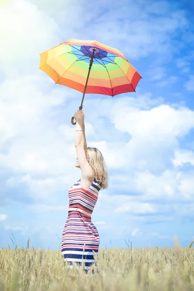 Прекрасная юная леди поднимает радужный зонтик на золотом пшеничном поле — стоковое фото