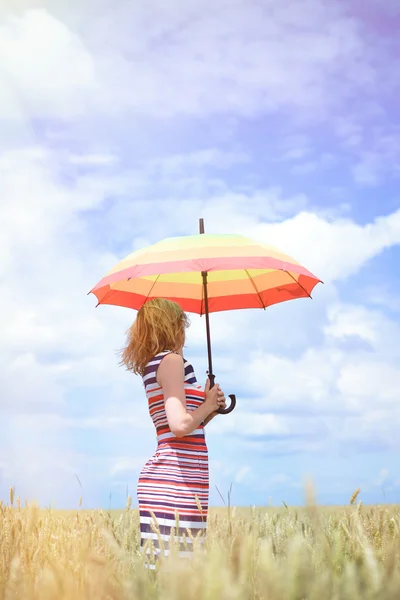 Beautiful young female standing with colorful umbrella on wheat field — Stock Photo, Image