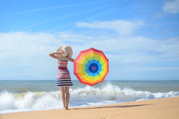 Backview av vackra damen med rainbow paraply sunning på havsstranden — Stockfoto