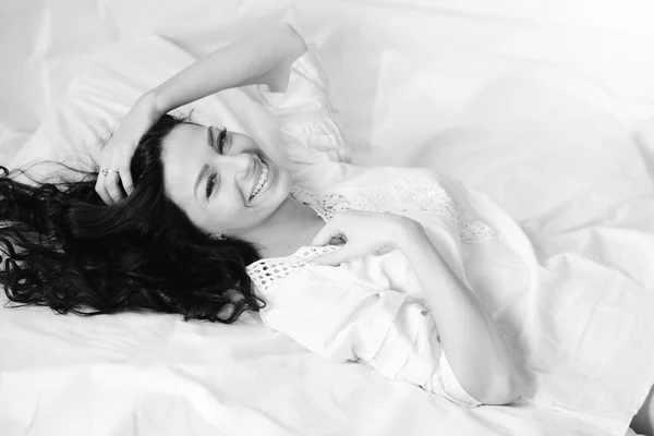 Черно-белая фотография сексуальной симпатичной девушки в отличной форме, весело отдыхающей, лежа в постели — стоковое фото