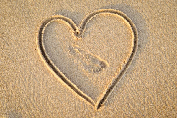 Heart handwrited on golden sand with foot print in it — Stock Photo, Image