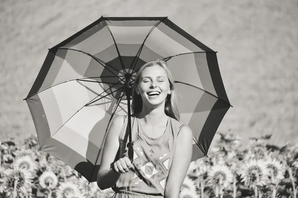 Black and white image of woman with umbrella beside sunflowers — Stok fotoğraf