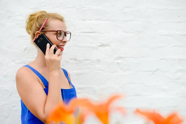 Beautiful young lady in big glasses speaking phone in garden — Stock Photo, Image