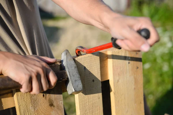 Primer plano de las manos con palanca y martillo reparación de valla de madera — Foto de Stock