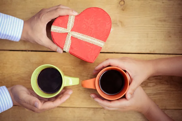 Closeup of mans hand giving heart-shaped giftbox to womans hands — Stock Photo, Image