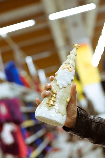 Fechar a mão segurando Papai Noel decoração de Natal na loja — Fotografia de Stock