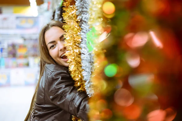 Jovem mulher bonita emocionante com guirlandas de Natal brilhantes na loja — Fotografia de Stock