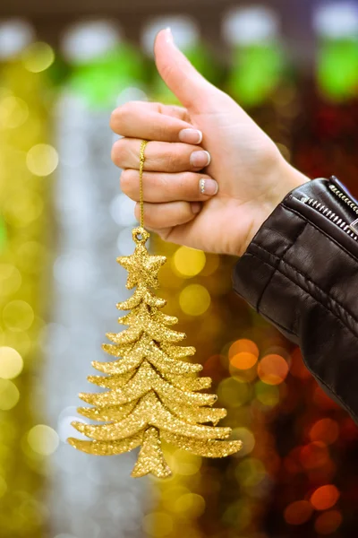 Closeup of hand holding golden christmas tree ornament in store — Stock Photo, Image