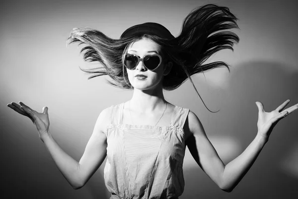 Retrato de cabelo menina surpreendida explodiu com óculos na forma de corações. Fotografia em preto e branco — Fotografia de Stock
