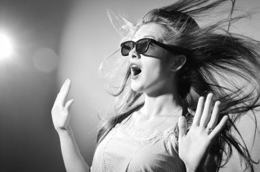 Black and white picture of surprised young beautiful lady in 3d glasses looking excited