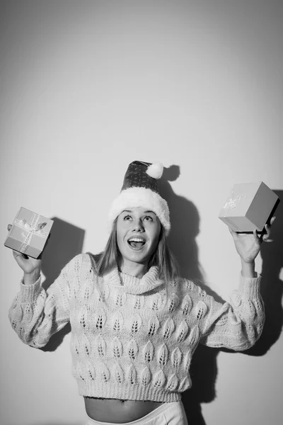 Black and white photography of exciting pretty girl in Santa hat with gifts — Stockfoto