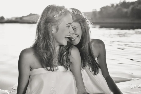 Black and white photography of 2 beautiful princess young ladies in white dresses on summer water outdoors background — Stock Photo, Image