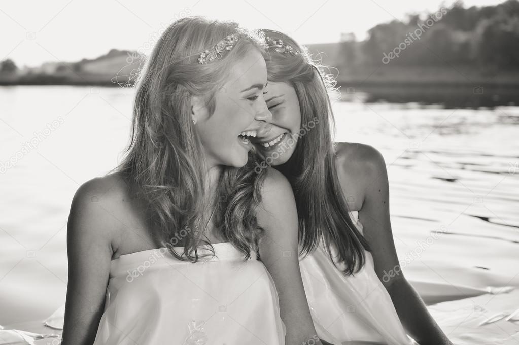 Black and white photography of 2 beautiful princess young ladies in white dresses on summer water outdoors background
