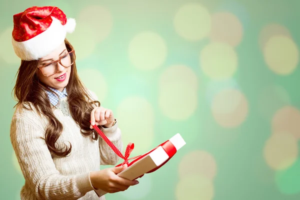 Picture of pretty girl in Santa red hat and glasses opening gift box — Stock Photo, Image