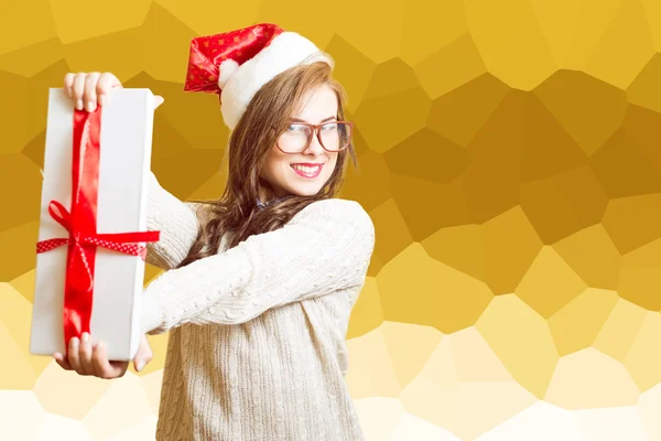 Portrait of beautiful young lady in Santa red hat and glasses showing gift box — Stockfoto