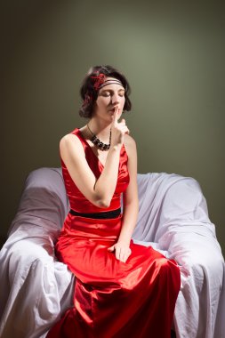 Portrait of Emotional Beautiful Woman In Red Dress Sitting In The Chair