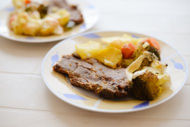 Plates with beautiful pork steak and sweet potatoes on table