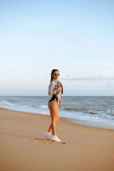 Mulher bonita em macacão e óculos de sol na praia à beira-mar — Fotografia de Stock