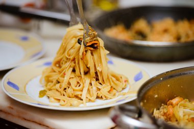 Serving beautiful traditonal pasta with seafood on plate in kitchen