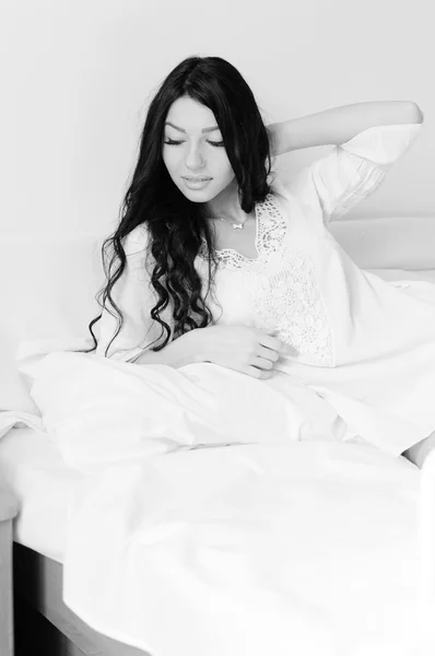 Imagen de una hermosa joven divirtiéndose feliz relajándose acostada en la cama posando sobre el fondo del espacio de copia de luz — Foto de Stock