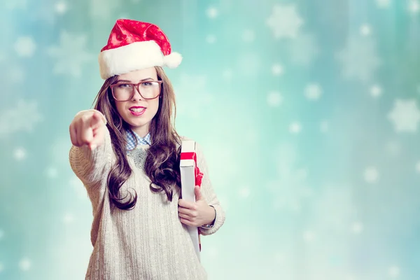 Imagem de apontar o dedo e segurando presente caixa bela jovem senhora em chapéu de Papai Noel em abstrato design de fundo festivo — Fotografia de Stock