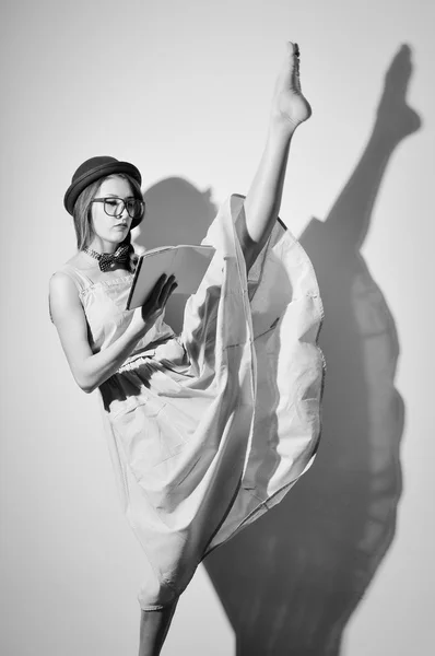 Portrait of elegant gymnast in a hat and glasses reading a book — Stock fotografie