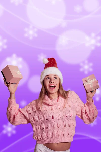 Joyful blonde lady in Santa hat holding two wrapped Christmas giftsboxes — Stockfoto