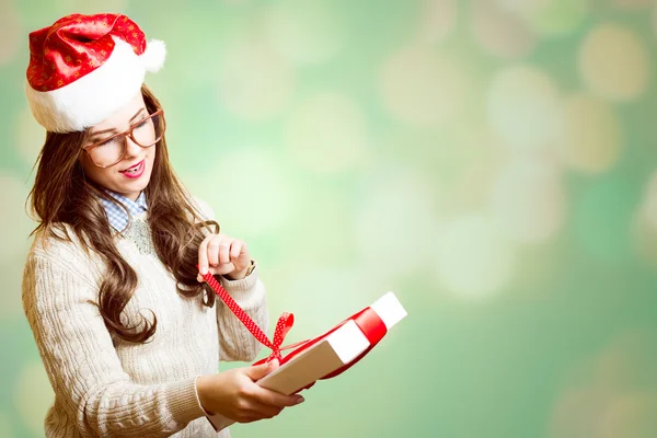 Picture of pretty girl in Santa red hat and glasses opening gift box — Stock Photo, Image