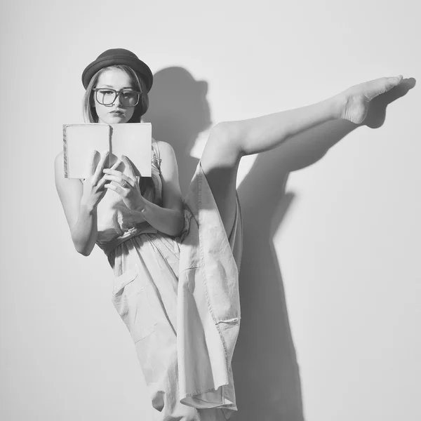 Portrait of elegant gymnast in a hat and glasses reading a book — Stock Fotó