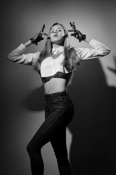 Black and white photography of blonde female in transparent gloves posing in jeans — Zdjęcie stockowe