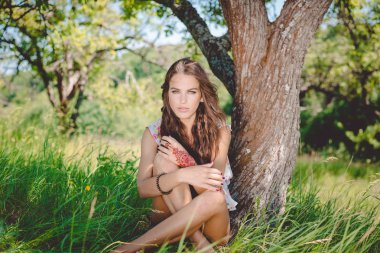 Joyful glamour young pretty lady relaxing sitting on the grass and happy looking at camera, portrait