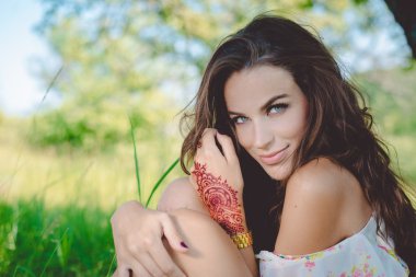 Joyful glamour young pretty lady relaxing sitting on the grass and happy looking at camera, portrait