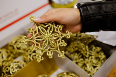 Closeup of hand holding golden snowflake glittered ornament in store