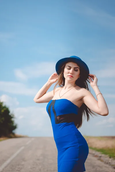 Elegant pretty girl on empty road looking at camera on blue sky copy space background, portrait — 스톡 사진