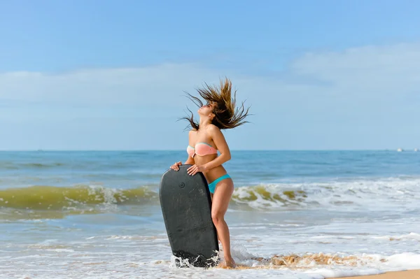 Belle jeune femme debout avec planche de surf noire sur bord de mer ensoleillée — Photo