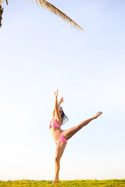 Emocionada chica bonita en bikini rosa bailando al lado de una gran palmera — Foto de Stock