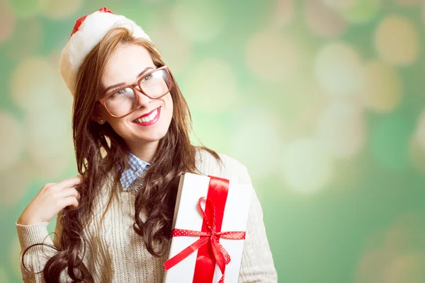 Picture of beautiful young lady in Santa red hat and glasses holding gift box — Stockfoto