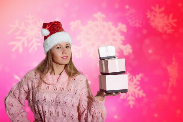 Menina bonita mostrando caixas de presente sob a neve no fundo borrado — Fotografia de Stock