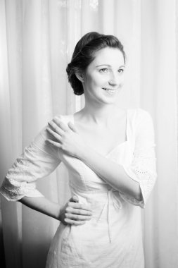 Picture of elegant beautiful young lady in white dress happy smiling and looking up on copy space tulle curtain background