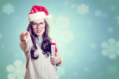 Picture of pointing finger and holding present box beautiful young lady in Santa Claus hat on abstract festive background design