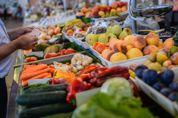 Hombre comprando frutas y verduras frescas en un puesto de mercado abierto — Foto de Stock