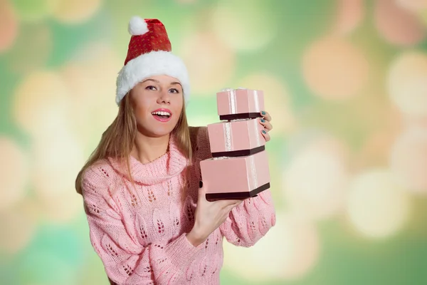 Smiling lady in Santa hat holding three Christmas gifts boxes — ストック写真