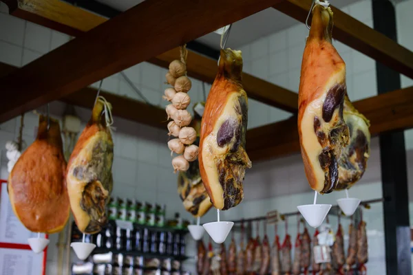 Delicious dry smoked pork legs hanging down at meat shop — 스톡 사진