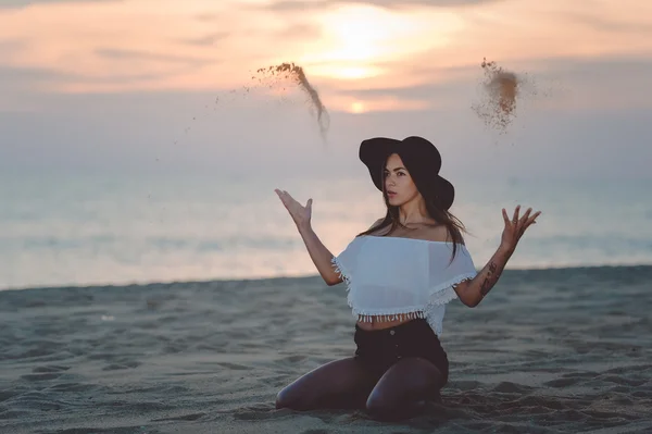 Elegant lady in floppy hat throwing sand sitting on seacoast — Φωτογραφία Αρχείου