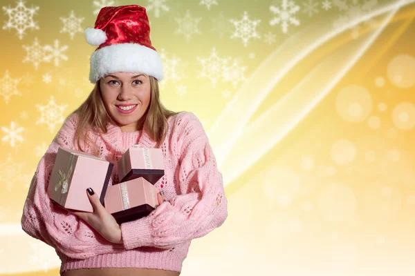 Glückliche Dame mit Weihnachtsmütze mit Geschenken auf gelbem Hintergrund — Stockfoto